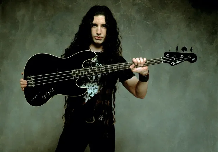 Long-haired musician holding black bass guitar